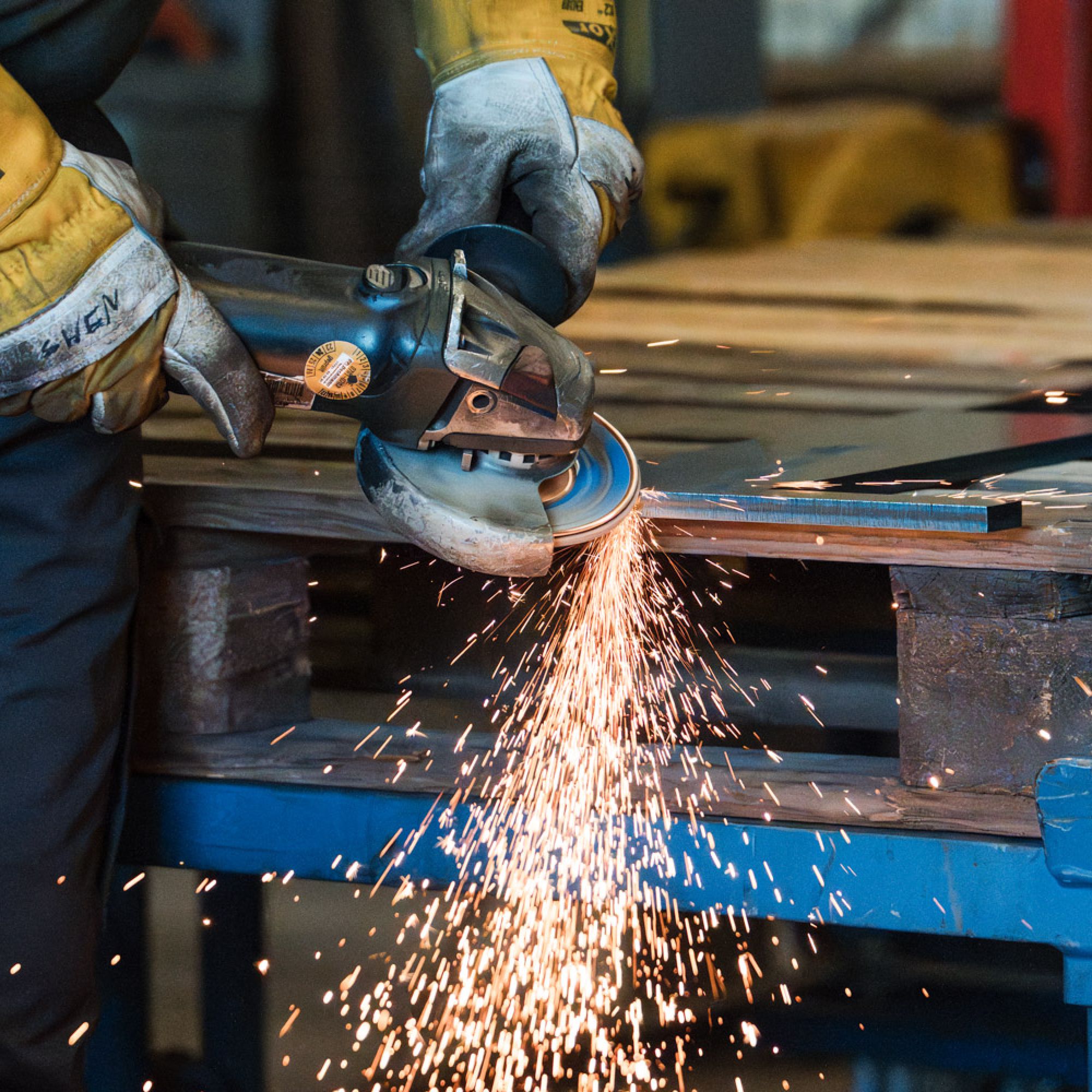 Mitarbeiter bearbeitet Metall mit Winkelschleifer